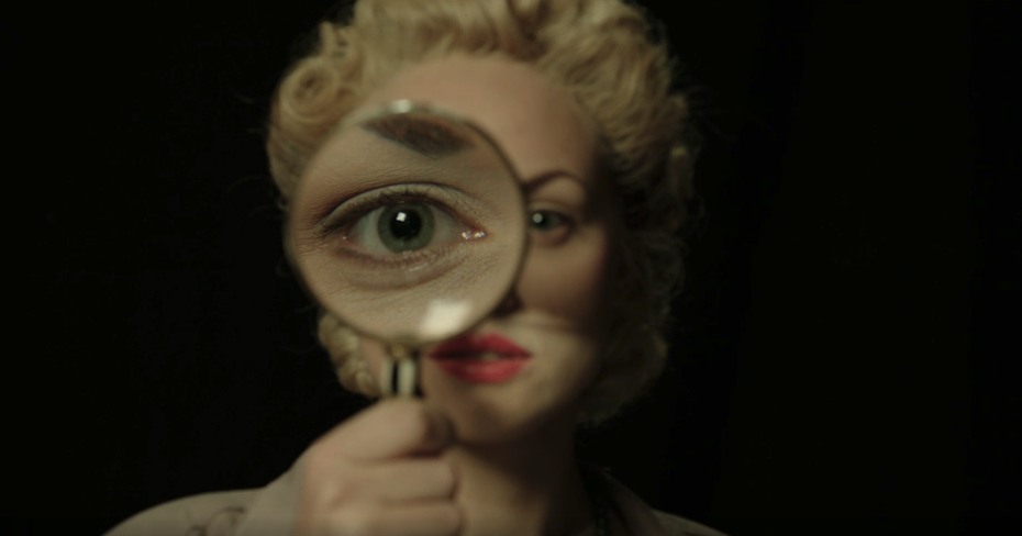 Elvira Slate investigator holding a magnifying glass up which enlarges eye