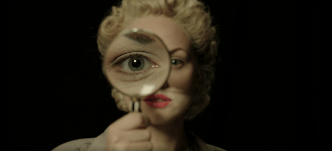 Elvira Slate investigator holding a magnifying glass up which enlarges eye